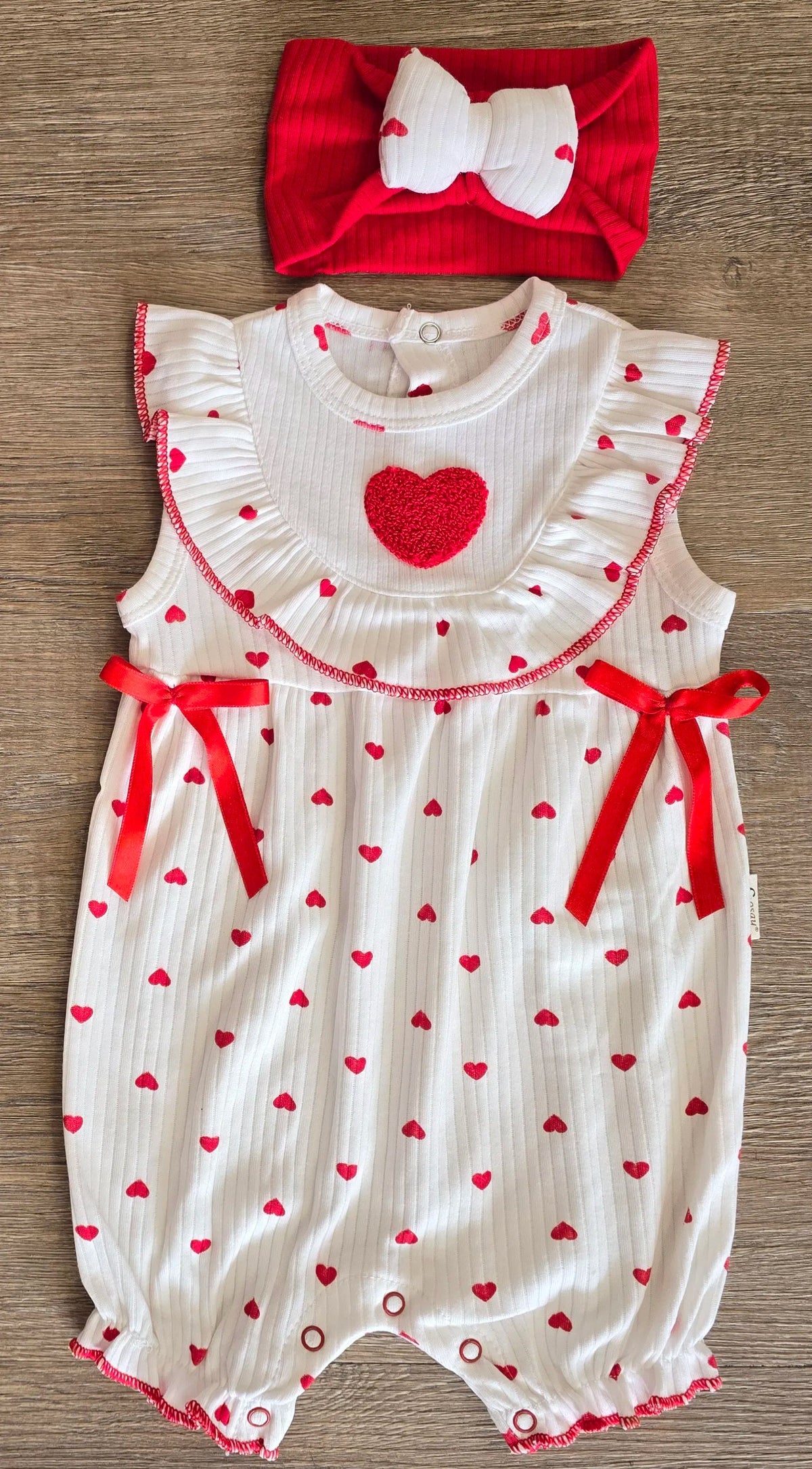 Détail barboteuse bébé fille col volanté et nœuds satinés