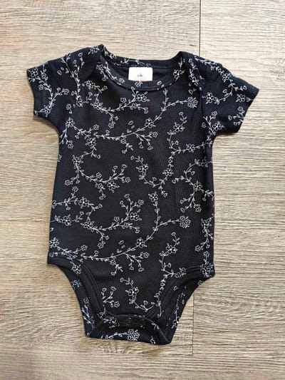 Détail body bébé blanc fleuri en coton