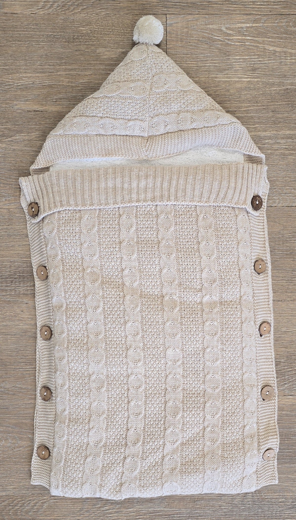 Nid d’ange bébé en laine beige avec capuche et pompon